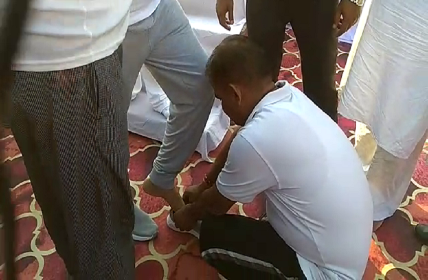 Yogi's Minister ties the shoe lace from worker