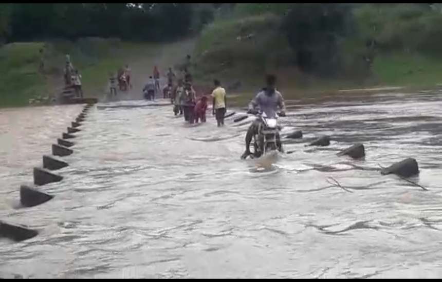 Video: जान खतरे में डालकर बाइक से और पैदल उफनती नदी पार कर लोग