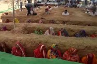 women farmers sit neck deep in pits