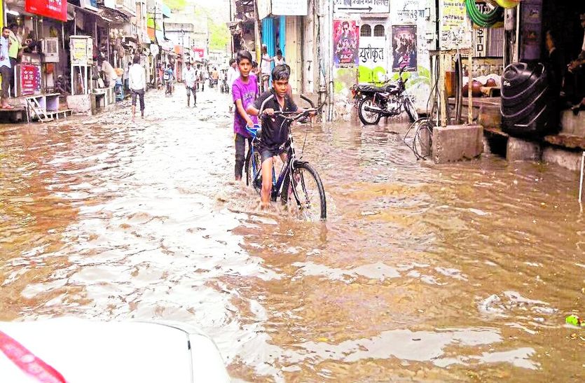 पानी में साइकिल ले जाते बच्चे।