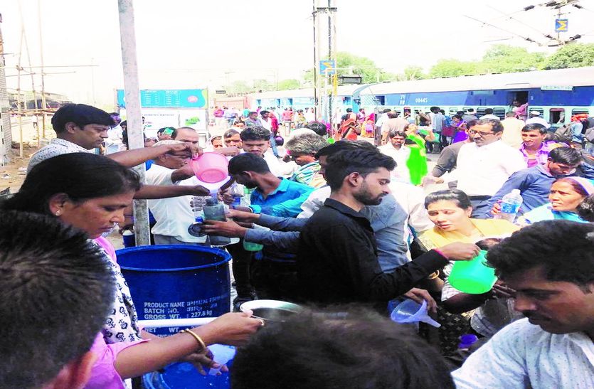 यात्रियों को पानी पिलाते लोग।
