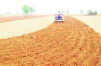 बारिश के बाद खेत में जुताई करता ट्रैक्टर 