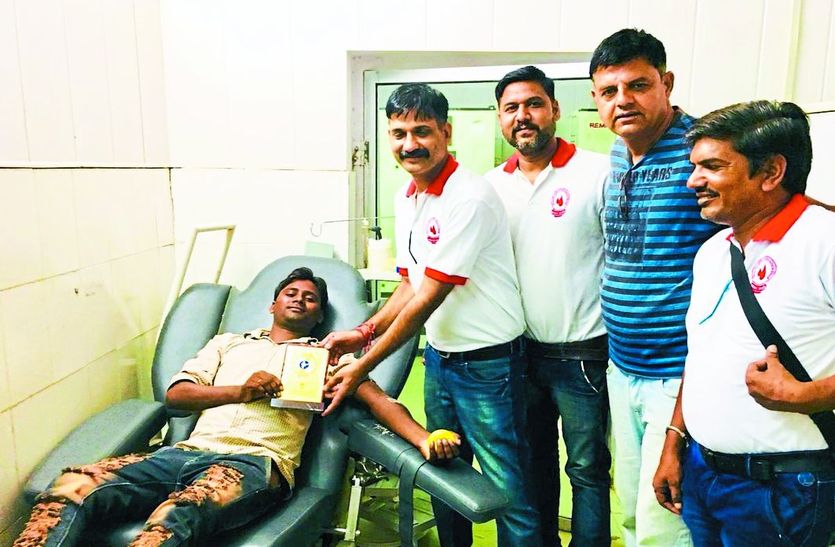 रक्तदाता को सम्मानित करते आयोजक ।