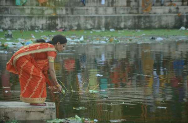 गंदगी बीच पूजा करती महिला 