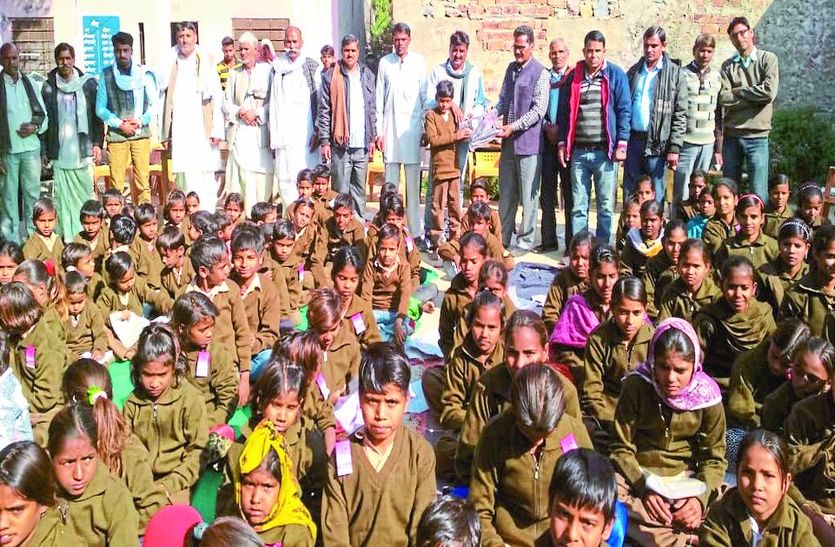 वितरित करते विद्यालय स्टाफ के साथ ग्रामीण।