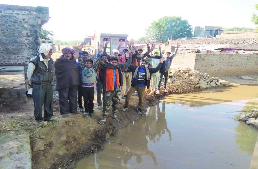 मिट्टी के अवरोधक पर विरोध जताते ग्रामीण एवं भरा पानी