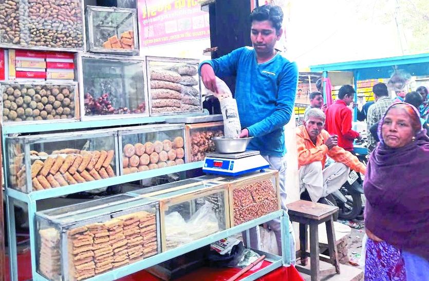एक दुकान पर गजक बेचता दुकानदार।