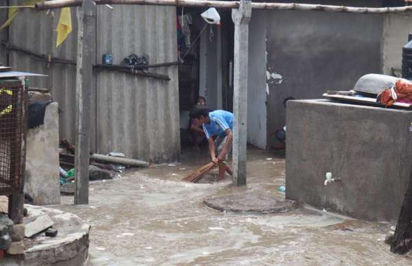 गुजरातः घरों में घुसे पानी को बाहर निकालते स्थानीय लोग