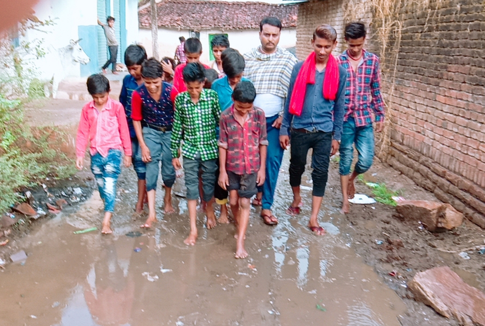  Children go to school from roadside mud to the knees in the rain