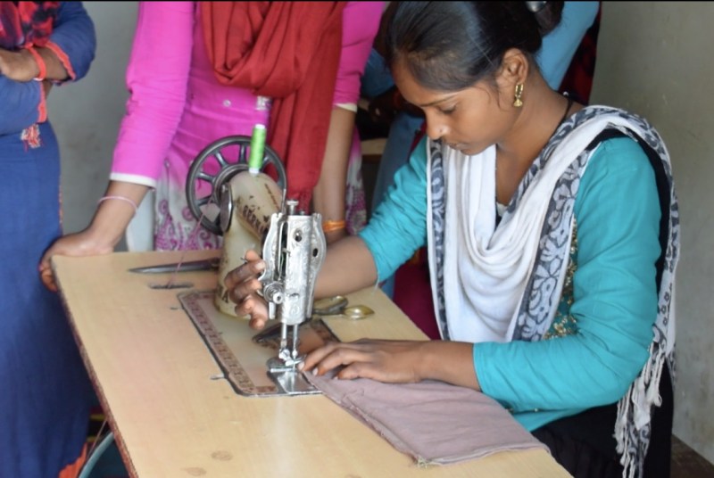 सूती कपड़ों से नैपकिन पैड बनाना सीखती किशोरी