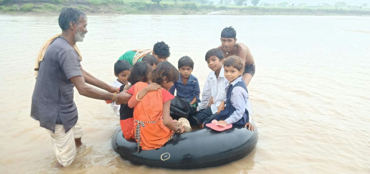 स्कूल जाने के लिए ट्यूब पर बैठकर नदी पार कर रहे हैं बच्चे