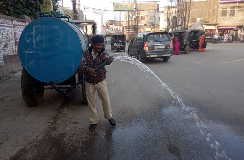 Municipal Corporation employees spraying water on the road near Mission Chowk.