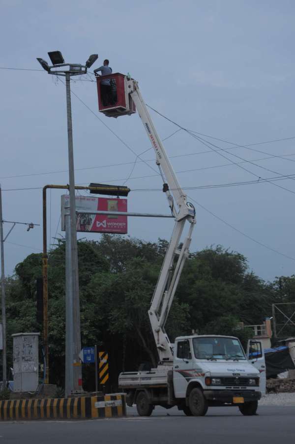 ग्वालियर आकाशवाणी चौराहे पर बिजली के पोल पर हाई मास्क सेट करता हुआ बिजली कर्मचारी