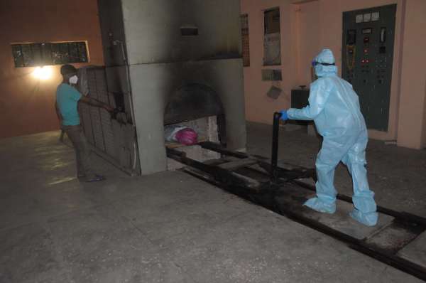 विद्युत शवदाह गृह का गेट खोल कर उसमें ट्रॉली को धकेला जाता है