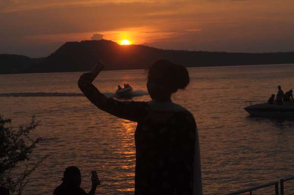 सुहाने मौसम में सन सेट  के साथ सेल्फी लेती हुई युवती