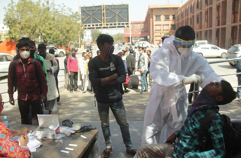अहमदाबाद शहर के कालूपुुर रेलवे स्टेशन पर बाहर से आने वाले नागरिकों की कोरोना जांच करता स्वास्थ्य कर्मचारी।