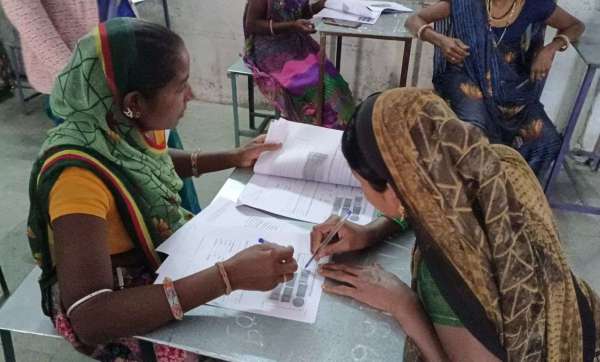 राउमावि चिडि़यावासा में निरक्षर महिला के पर्चे में लिखती दूसरी महिला।