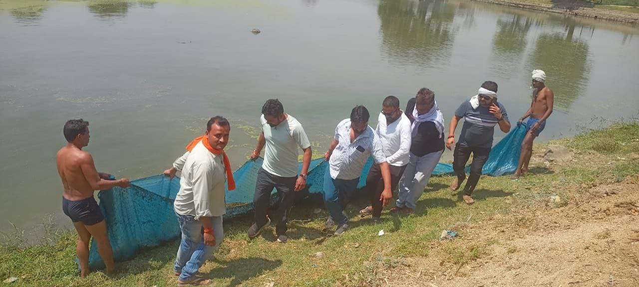 जाल की मदद से पानी के अंदर का कचरा निकालते श्रमदानी