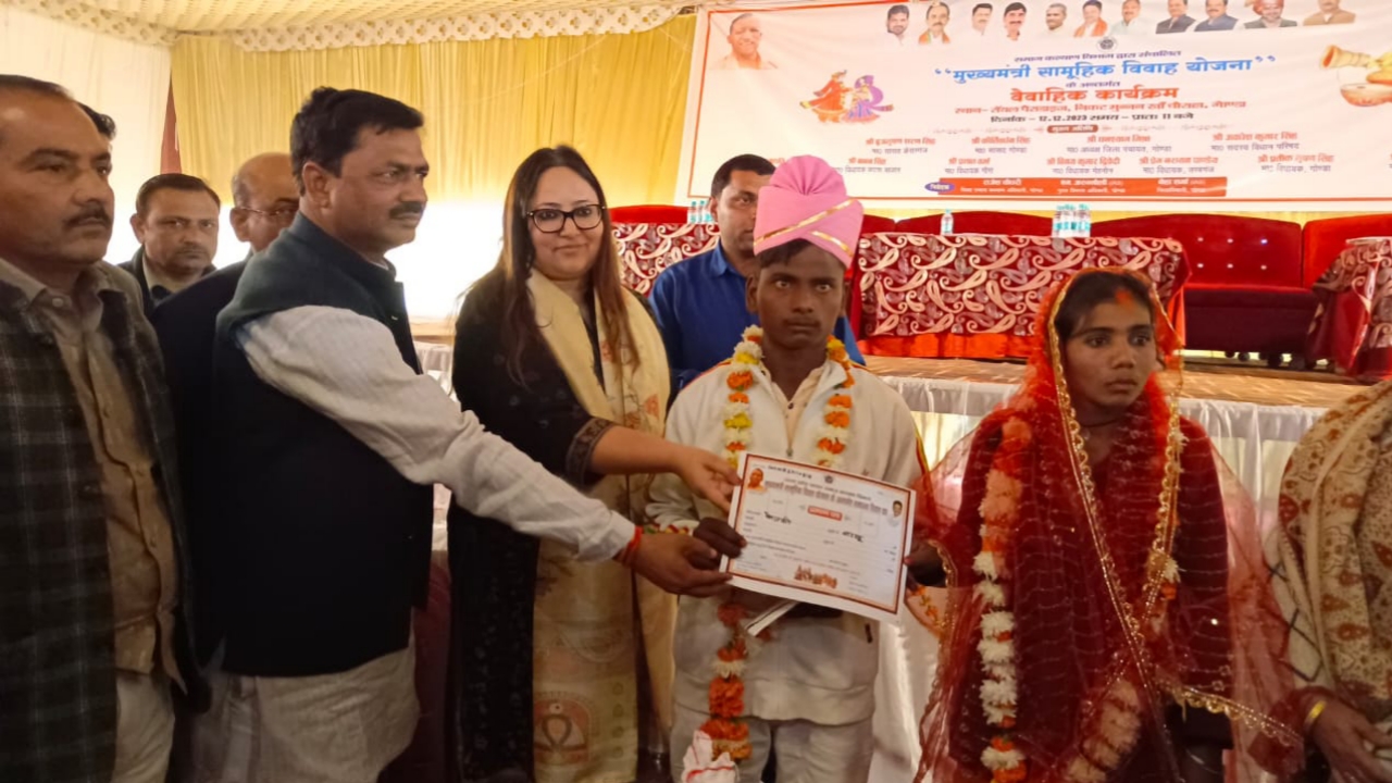 मुख्यमंत्री सामूहिक विवाह योजना में प्रमाण पत्र देता जिलाधिकारी और अन्य