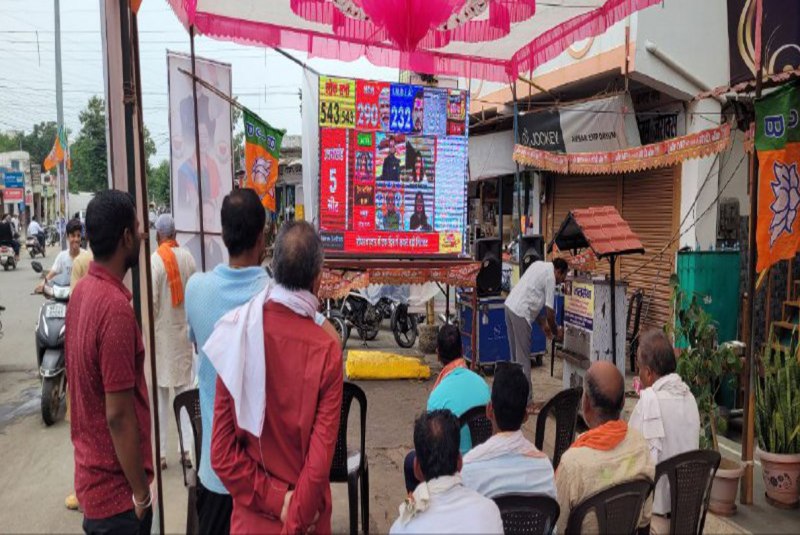 स्क्रीन पर लोग देश भर के चुनावी नतीजों को देख रहे हैं।