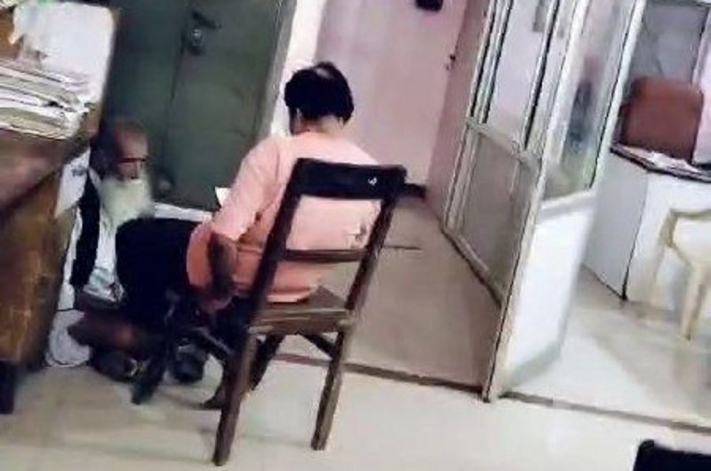 वृद्ध से पैरों की मालिश कराते हुए शाखा प्रबंधक