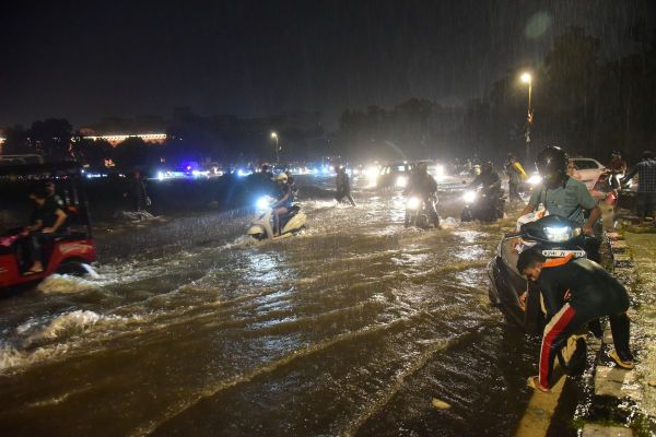 जलभराव के बीच जान जोखिम में डालकर वाहन चलाते चालक