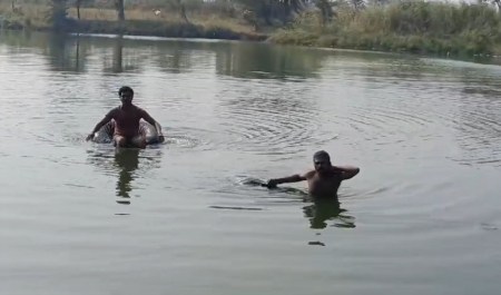 शव को नदी से बाहर निकलाते गोताखोर