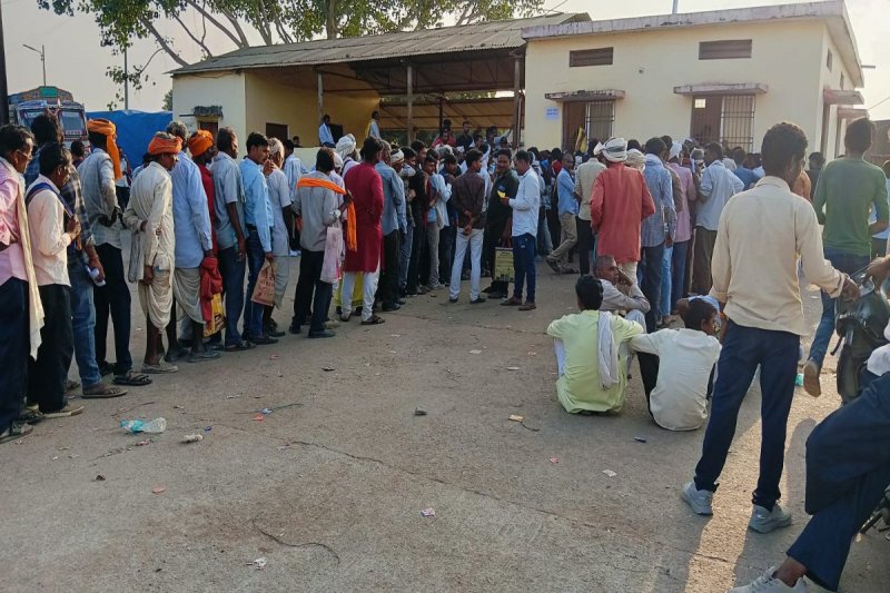 लाइन में खड़ी महिलाएं और पुरुष।