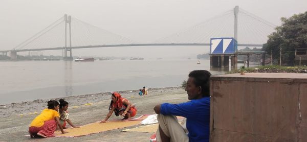 छठ पूजा के लिए महानगर के बाबूघाट पर गेहूं सुखाती महिलाएं