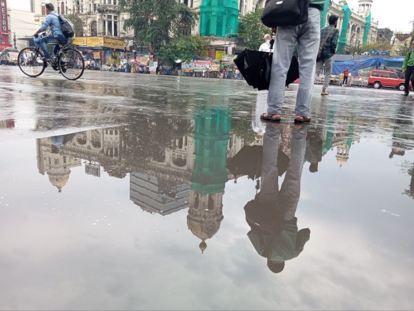 कोलकाता के धर्मतल्ला में जलभराव से गुजरते लोग।