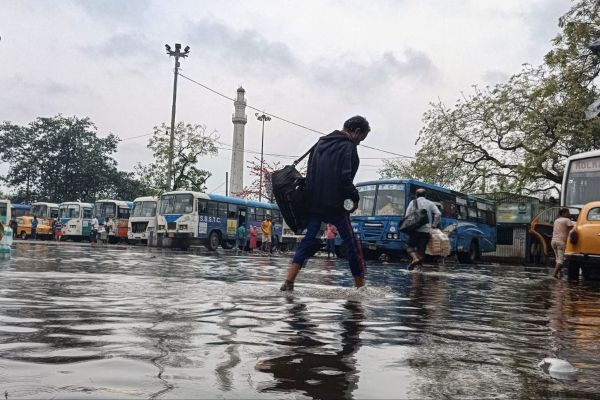कोलकाता के धर्मतल्ला के बस स्टैंड पर जलभराव से परेशान लोग।