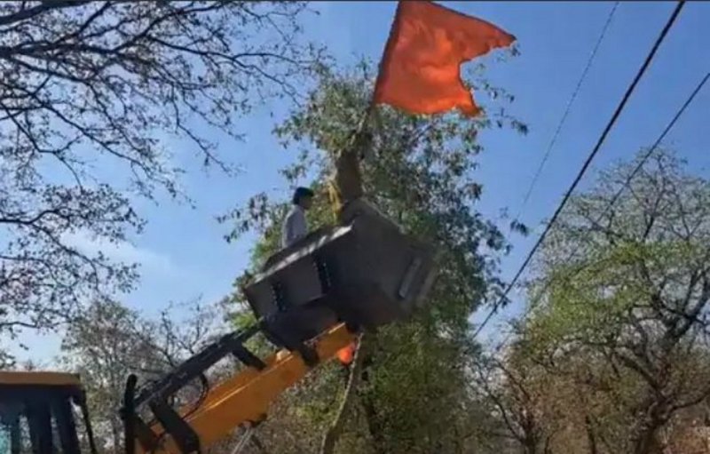 जेसीबी से ध्वजा फहराता श्रद्धालु।