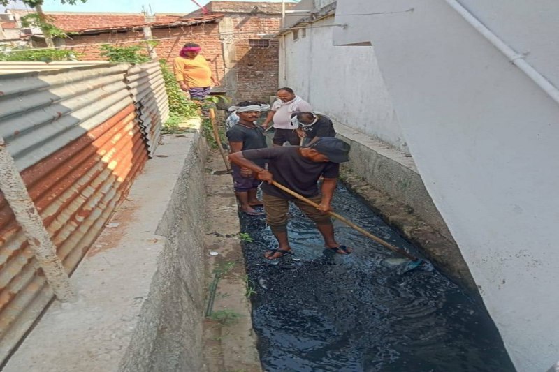 नाले में उतरकर सफाई करते नगर पालिका कर्मचारी।