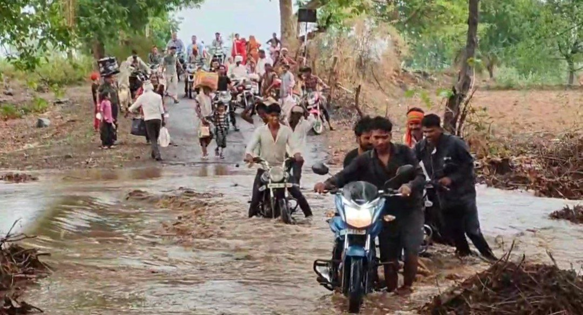 बाढ़ के पानी के बीच जान जोखिम में डालकर ग्रामीणों ने पार किया रपटा