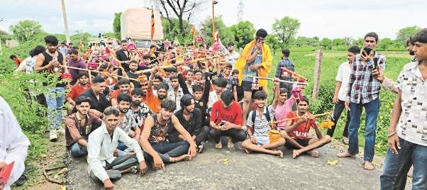 बूबानी रोड पर धरने पर बैठकर पुलिस के खिलाफ विरोध प्रदर्शन करते कांवड़िए।