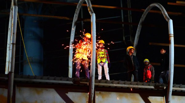 मल्टीलेवल पार्किंग के दूसरे तल से जोड़ने वाले गर्डर पर लगे एंगल की बिल्डिंग कराते श्रमिक।