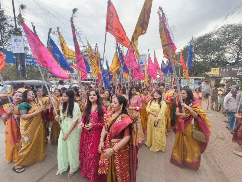 निशान यात्रा में श्रद्धा का रंग: हाथों में निशान लिए सहभागी महिलाएं।