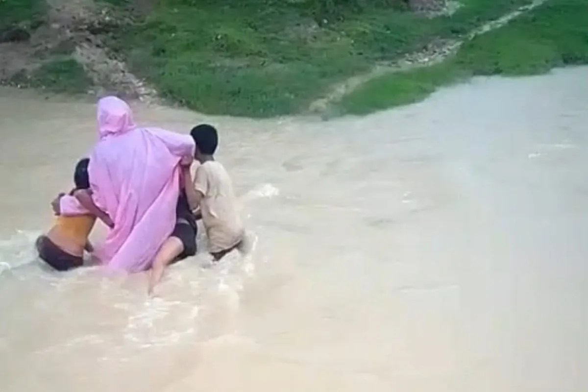 Children cross swollen drain