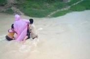 Children cross swollen drain