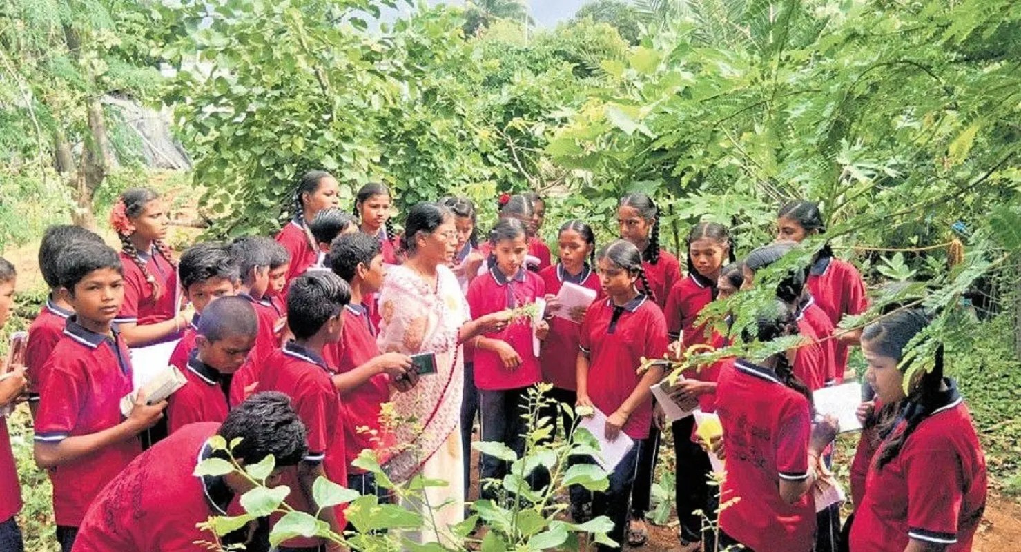 कर्नाटक के गदग के हेसरूर गांव में सुनंदा चिगारी के बगीचे में विभिन्न पौधों और फलों की प्रजातियों की जानकारी लेते स्कूली विद्यार्थी।