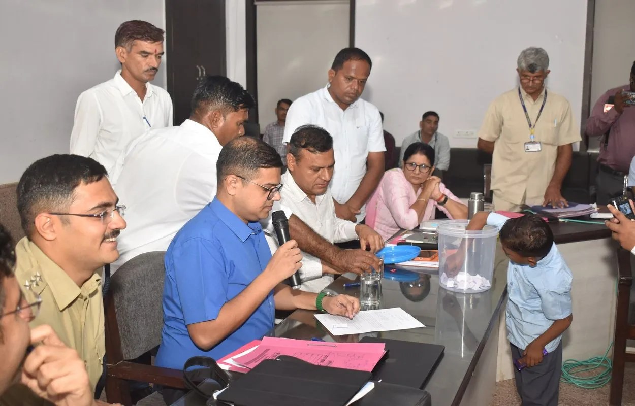जिला कलक्टर की अगुवाई में वार्ड आरक्षण की लॉटरी निकालते हुए बच्चा।