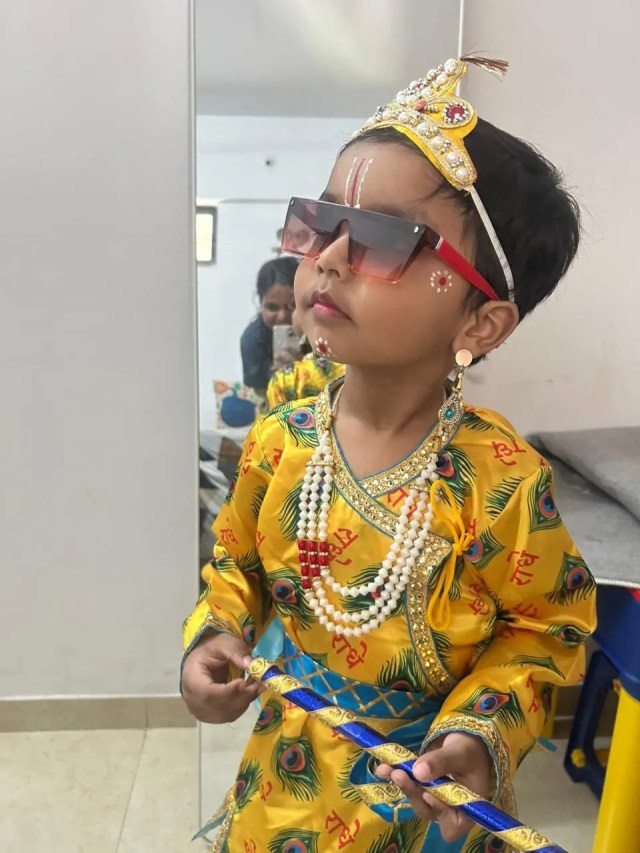 
चश्मे के पीछे चमकती आंखें, सिर पर मकुट और हाथ में बांसुरी... ध्वनित सिंह गुप्ता का कान्हा अंदाज बेहद खास।
मुंबई के कल्याण से आए चार वर्षीय ध्वनित ने राधे नाम की पोशाक में कृष्ण भक्ति की सुंदर छटा दिखाई।

