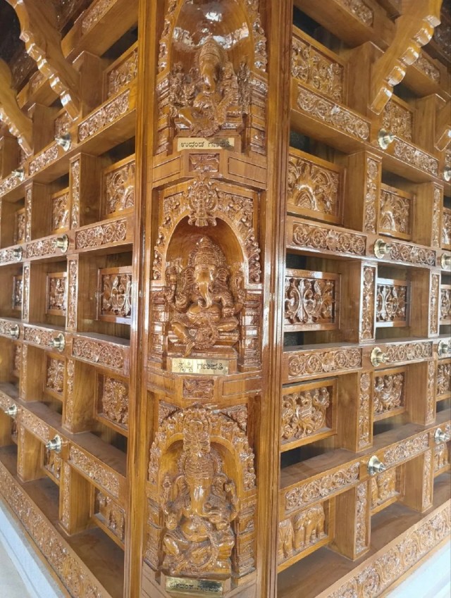 कला और आस्था का संगम: मंदिर की लकड़ी की सजावट में तीन-तीन की पंक्तियों में उकेरी गई गणेश प्रतिमाएं, जिनके नाम कन्नड़ भाषा में अंकित हैं।