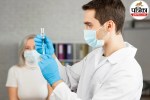 A lab technician holding a blood sample vial for a calcium test in a medical laboratory.