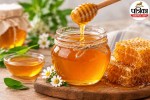 Glass jar of raw honey with wooden honey dipper on a wooden table, representing natural energy and health benefits.