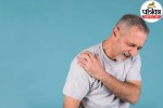 A person holding their shoulder in pain while experiencing sudden chest discomfort and breathlessness, indicating a medical emergency.