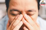 Close-up of a person experiencing eye irritation and inward-growing eyelashes (trichiasis) causing redness and watering.