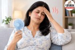 Menopause के दौरान हॉट फ्लैश से परेशान महिला, माथे पर हाथ रखकर पंखे से गर्मी दूर करती हुई।